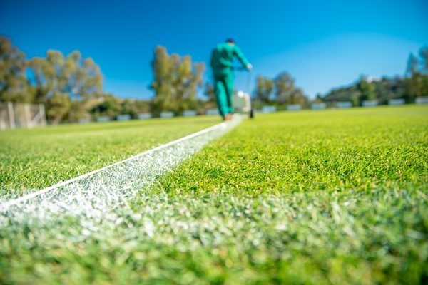 Striping machine painting fresh white lines on a green football field